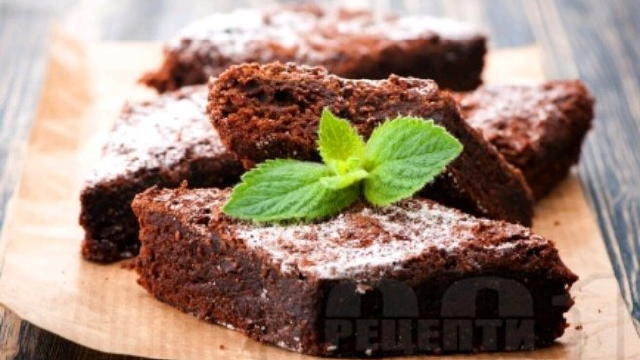 ентова хартия. В голяма купа комбинирайте шоколада, кокосовото масло и ги разтопете в микровълнова или на водна баня. Трябва да се получи гладка смес. Оставете я леко да се охлади. След това се прибавят бялата и кафява захар, яйцата и жълтъкът, ванилията.Разбъркайте добре и сложете сухите съставки. След като се получи хомогенна смес, изсипете я в тавата и печете за около 35 минути. Времето за печене може да се регулира,