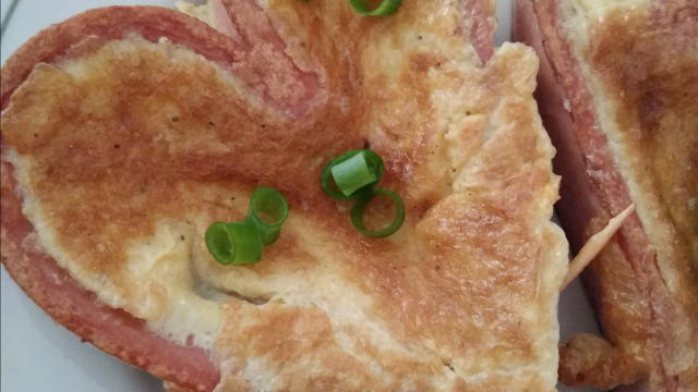 awiamy. Ser ścieramy i mieszamy z masą jajeczną.. ilość sera zależy od upodobań. Doprawiamy. Rozciętą parówkę wywijamy w serce i spinamy wykałaczką. Kładziemy na patelni i lekko rumienimy. W środę wylewamy jajko. Gdy się zetnie obracamy  smażymy drugą stronę. Dekorujemy szczypiorkiem.